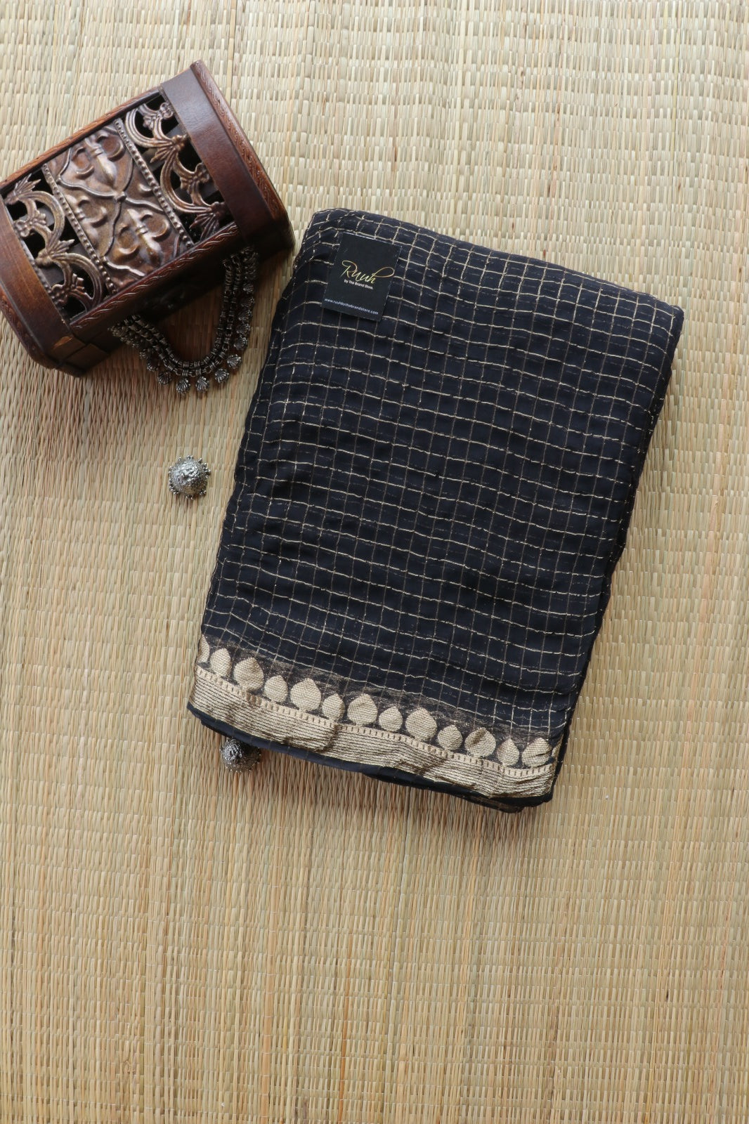 Black checkered fabric with decorative border on a textured surface